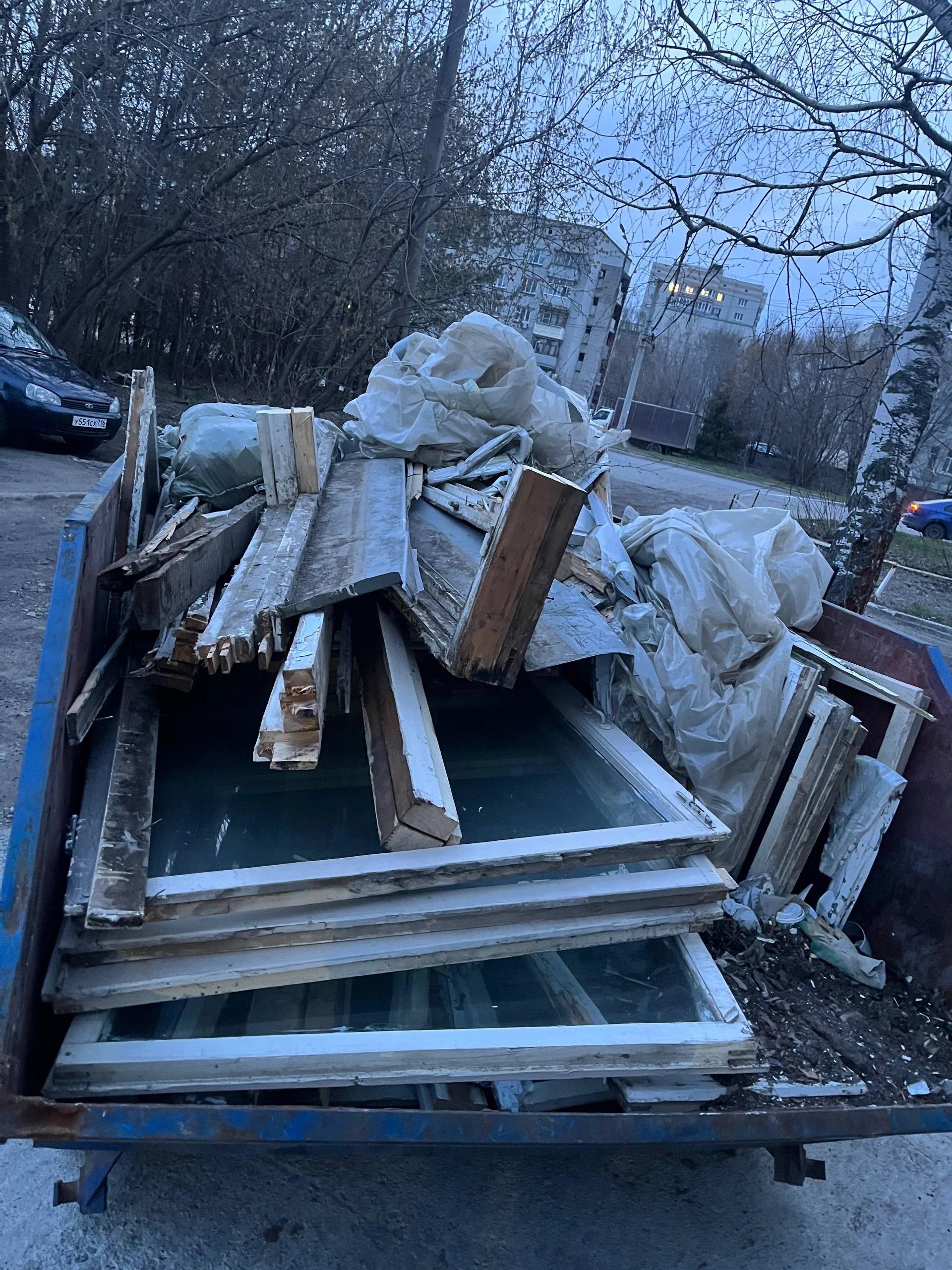 Контейнер со старыми окнами, деревом и мусором после ремонта — вывоз крупногабарита в жилом районе Казани