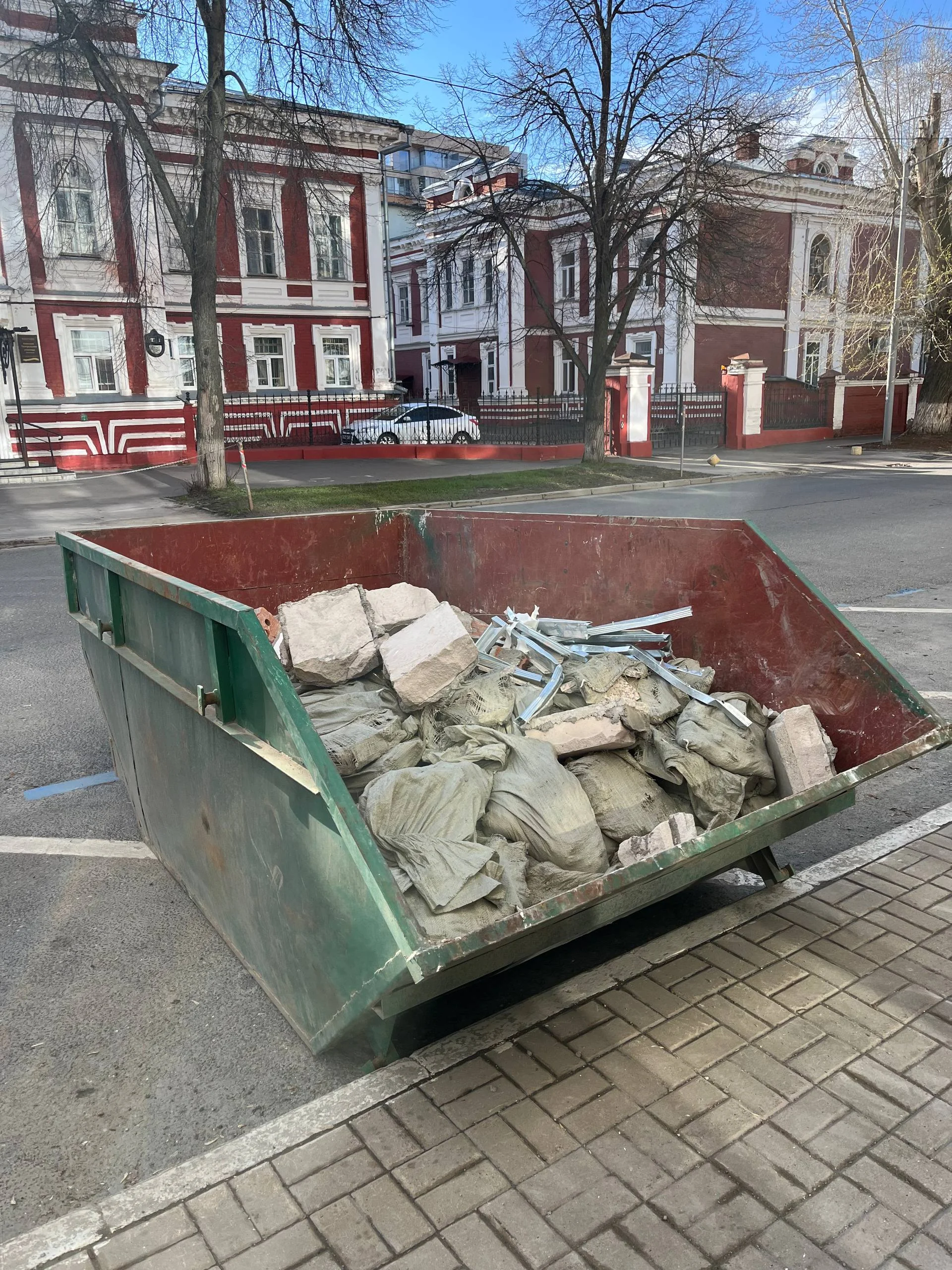 Вывоз строительного мусора в Казани: зелёный контейнер 8 м³ с мешками и ломом у дороги